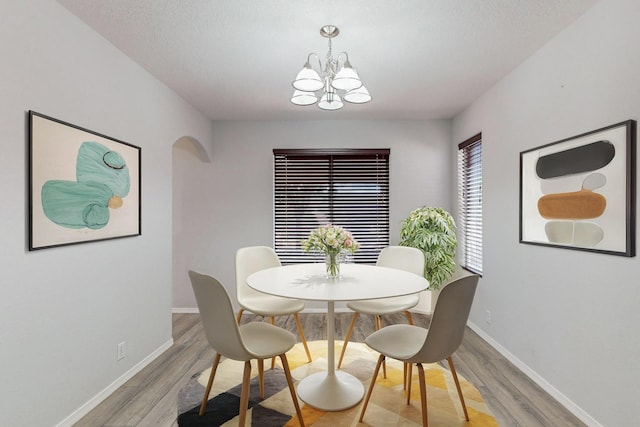 dining room featuring hardwood / wood-style flooring, a textured ceiling, and a chandelier