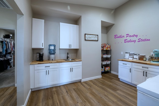 kitchen with light wood-type flooring, wood counters, and white cabinets