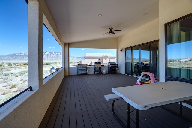 wooden deck featuring a mountain view, ceiling fan, and grilling area