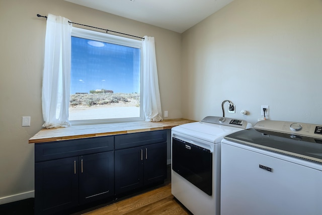 laundry area with cabinets, wood-type flooring, and washing machine and dryer