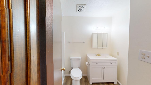 bathroom featuring vanity, toilet, and hardwood / wood-style flooring