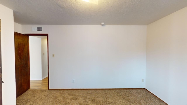 unfurnished room featuring a textured ceiling and light carpet