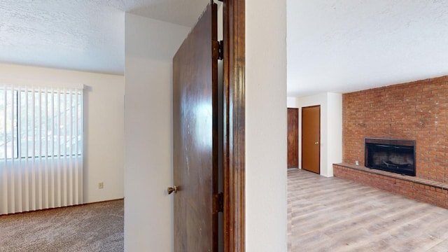 hallway with a textured ceiling and light colored carpet