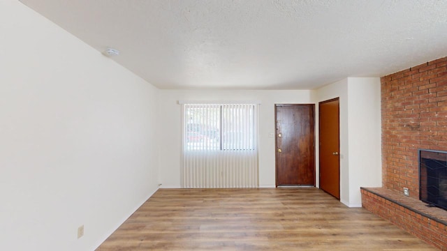 unfurnished living room featuring light wood-type flooring, a textured ceiling, and a fireplace