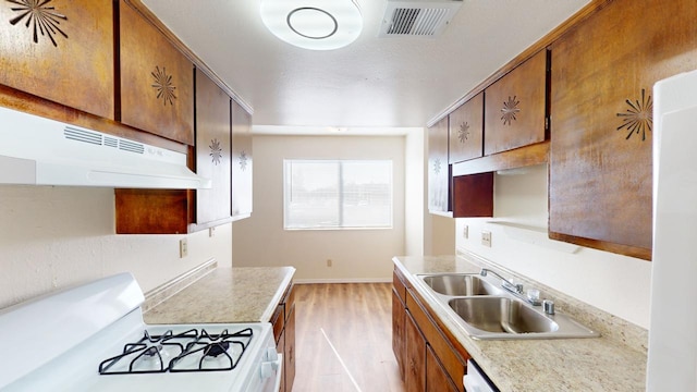 kitchen featuring light wood-type flooring, white gas range oven, and sink