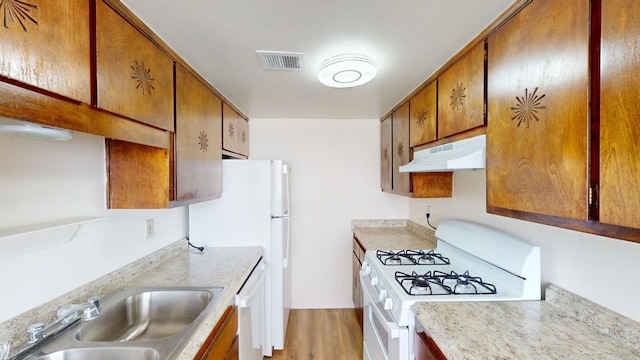 kitchen with white appliances, light hardwood / wood-style floors, and sink