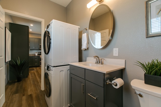 laundry area featuring sink, dark hardwood / wood-style flooring, and stacked washing maching and dryer