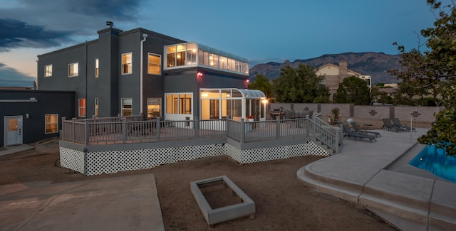 pool at dusk with a deck with mountain view and a patio area