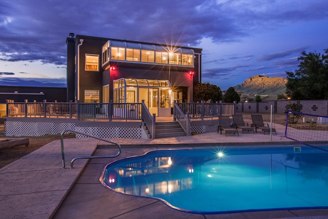 pool at dusk featuring a patio and a deck