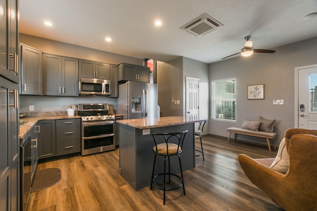 kitchen featuring a center island, dark hardwood / wood-style floors, appliances with stainless steel finishes, and light stone counters