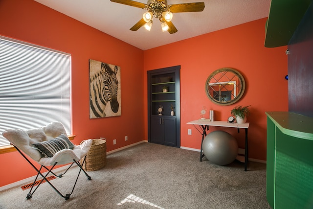 living area with carpet floors and ceiling fan