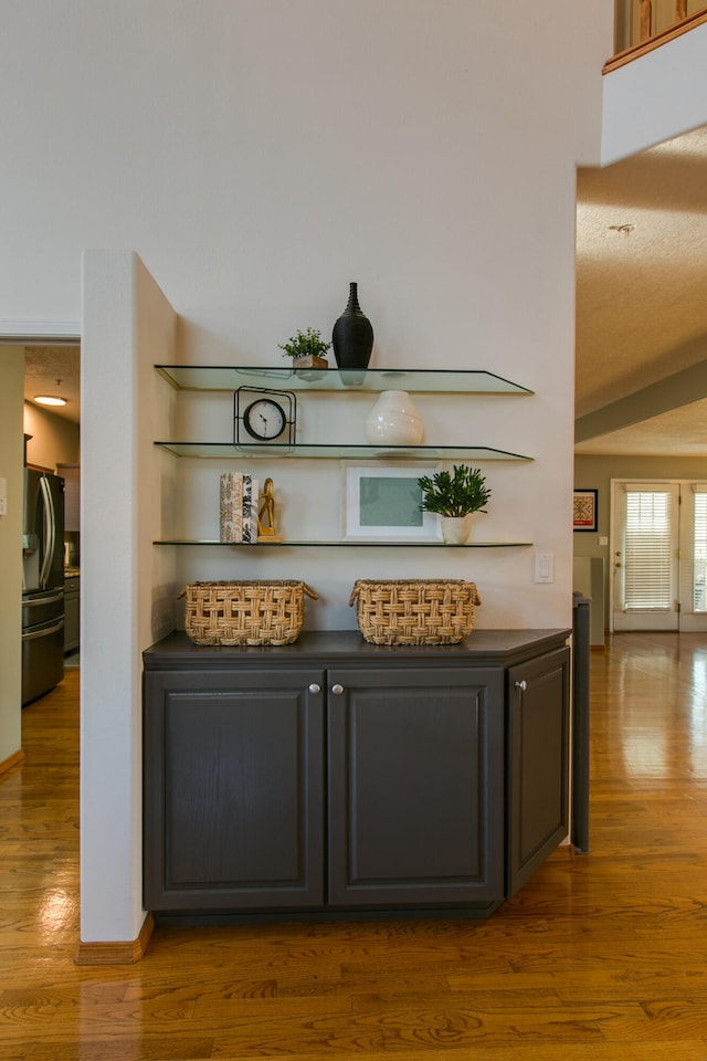 bar featuring wood-type flooring, stainless steel refrigerator, and vaulted ceiling