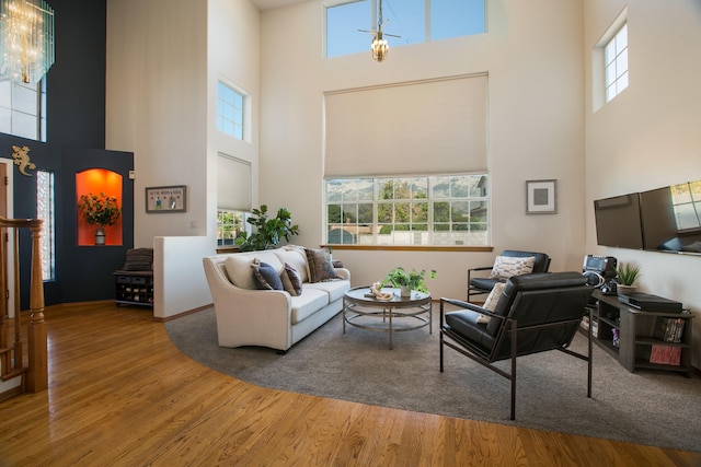 living room with wood-type flooring, a towering ceiling, and plenty of natural light