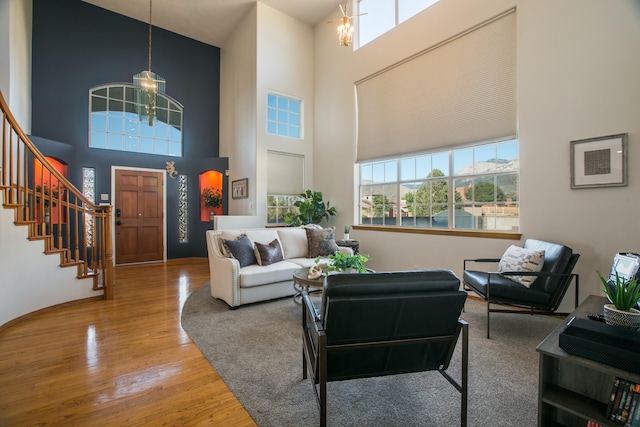 living room with a notable chandelier, a high ceiling, and hardwood / wood-style flooring