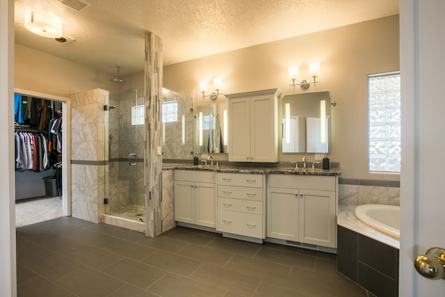 bathroom with vanity, shower with separate bathtub, a textured ceiling, and tile patterned floors