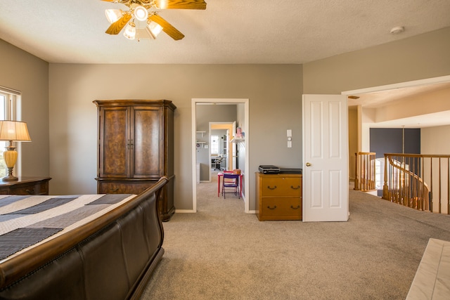 bedroom with ceiling fan, light colored carpet, and a textured ceiling