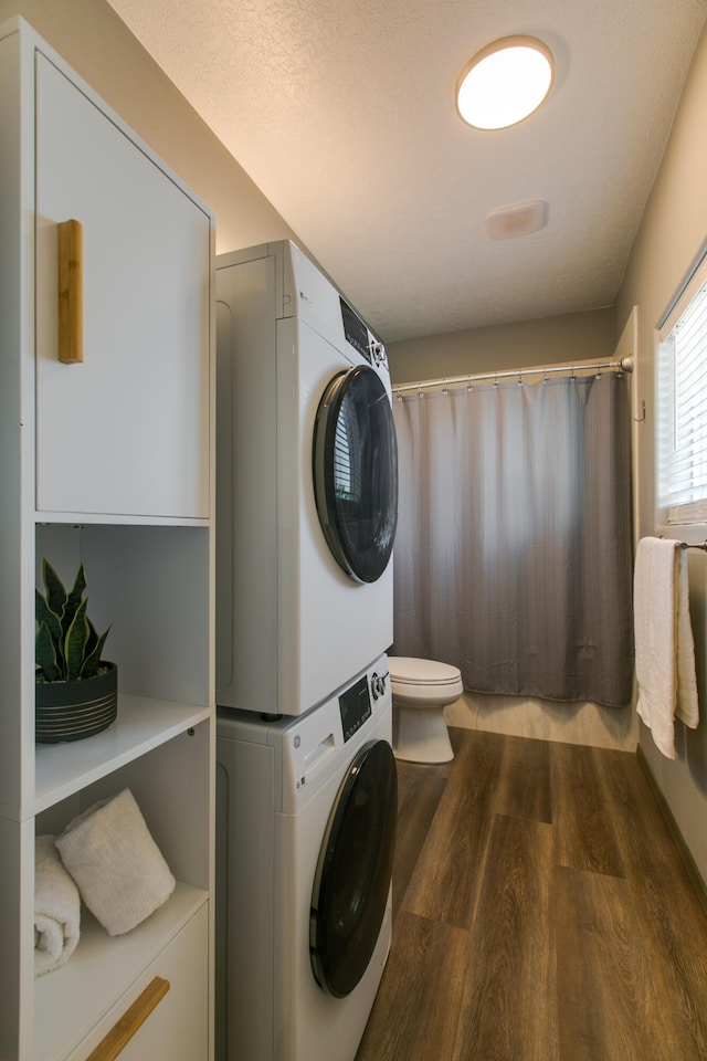 laundry area featuring a textured ceiling, stacked washing maching and dryer, and hardwood / wood-style flooring