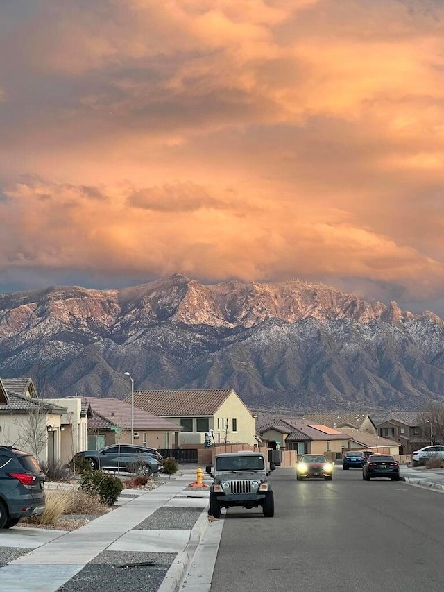 view of street featuring sidewalks, street lighting, a residential view, and a mountain view