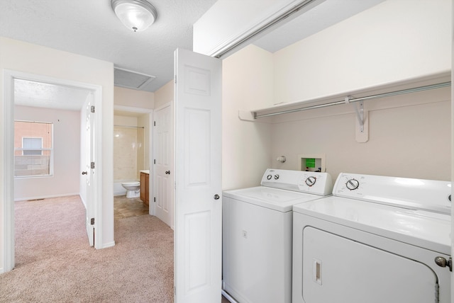 laundry area with washing machine and clothes dryer, a textured ceiling, and light carpet