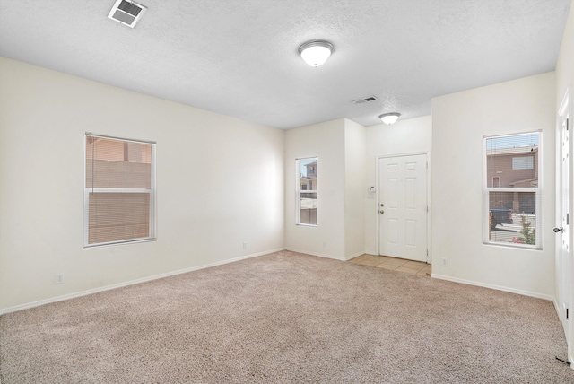 unfurnished room featuring a textured ceiling and light colored carpet