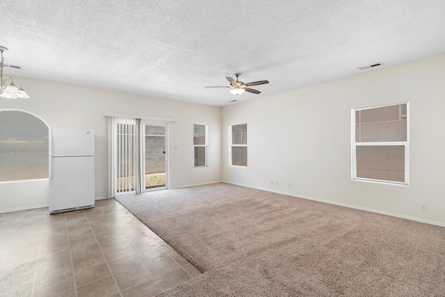 spare room featuring light carpet, a textured ceiling, and ceiling fan with notable chandelier