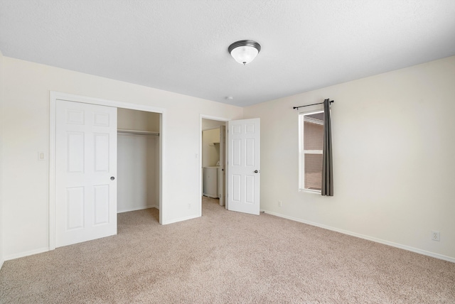 unfurnished bedroom with a textured ceiling, washer / dryer, light carpet, and a closet