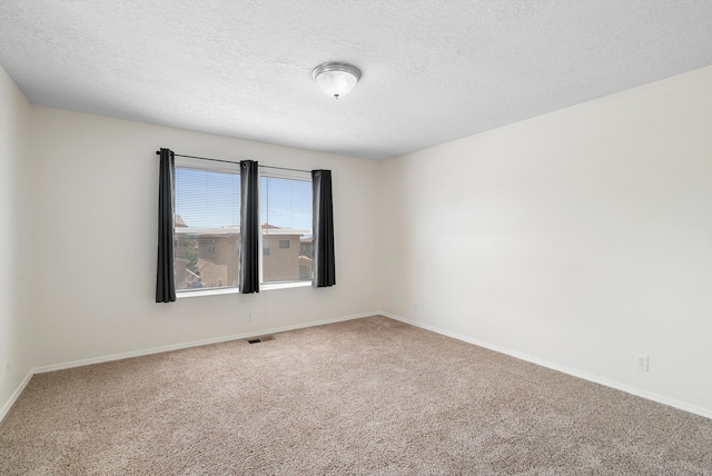 carpeted empty room featuring a textured ceiling