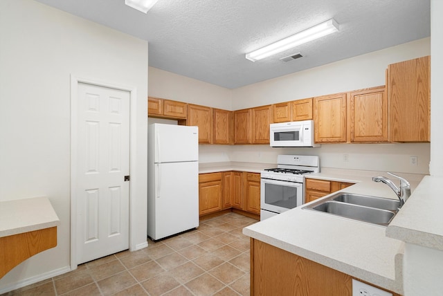 kitchen with light tile patterned floors, kitchen peninsula, sink, white appliances, and a textured ceiling