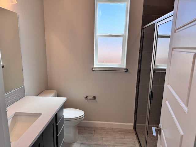 bathroom with vanity, toilet, a shower with door, and a healthy amount of sunlight