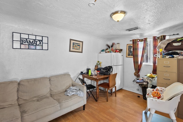 living room with a textured ceiling and light hardwood / wood-style floors