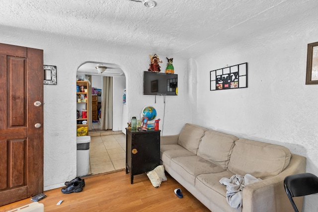 living room with a textured ceiling and light wood-type flooring