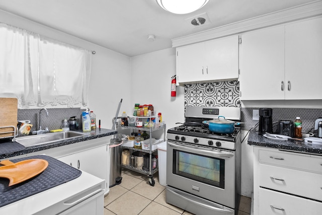 kitchen with white cabinets, light tile patterned flooring, sink, stainless steel range with gas cooktop, and decorative backsplash