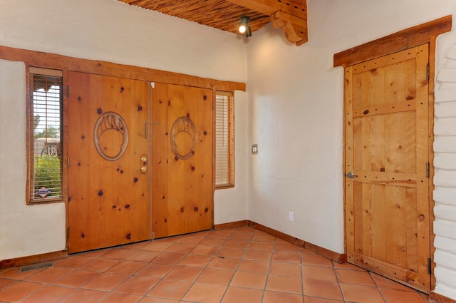 spare room featuring wood ceiling, beam ceiling, and light tile patterned floors