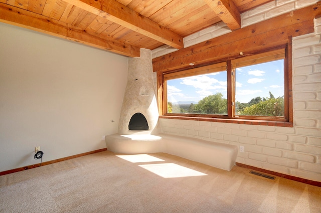 empty room featuring wooden ceiling, carpet, beamed ceiling, and brick wall