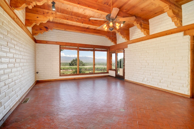 spare room featuring brick wall, a mountain view, wooden ceiling, and ceiling fan