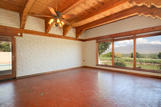 spare room with a mountain view, beam ceiling, ceiling fan, brick wall, and wooden ceiling