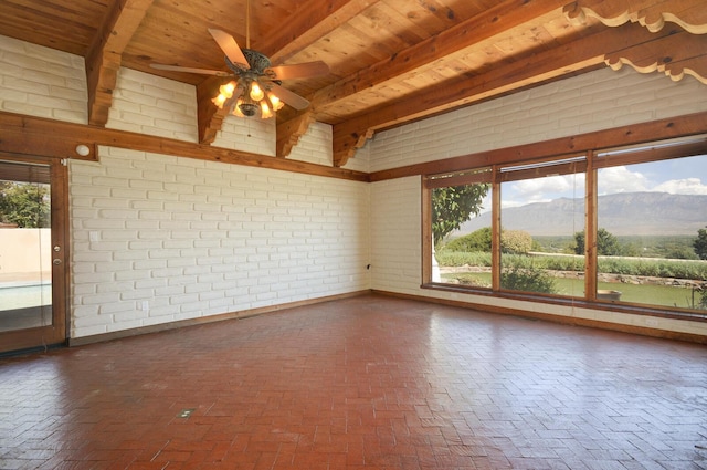spare room featuring brick wall, beam ceiling, a mountain view, and brick floor