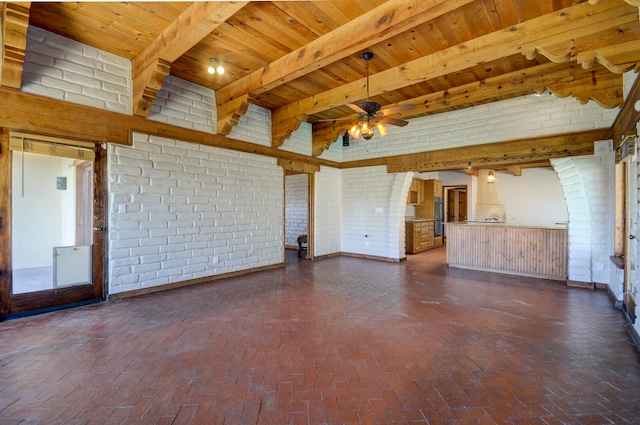 empty room with wood ceiling, ceiling fan, beamed ceiling, and brick wall