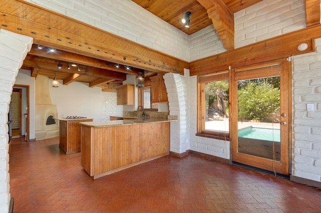 kitchen featuring beamed ceiling, wood ceiling, kitchen peninsula, brick wall, and a towering ceiling