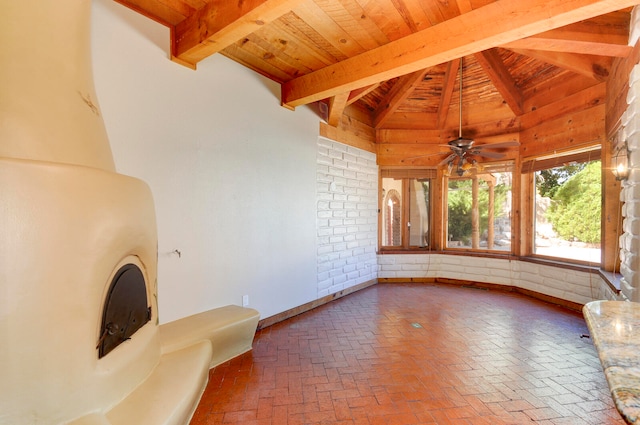 unfurnished living room with lofted ceiling with beams, wood ceiling, ceiling fan, and brick wall