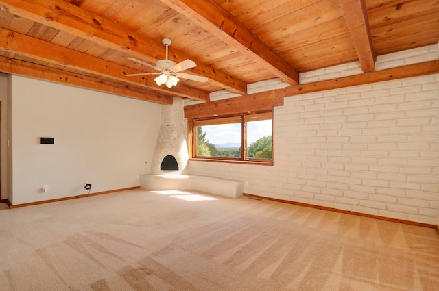 carpeted spare room with beamed ceiling, ceiling fan, brick wall, and wooden ceiling