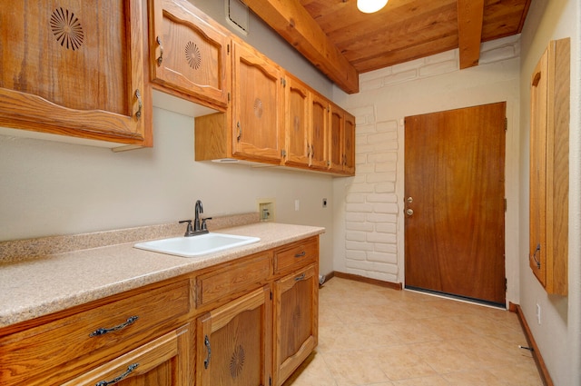 kitchen with wooden ceiling, light tile patterned flooring, sink, and beamed ceiling