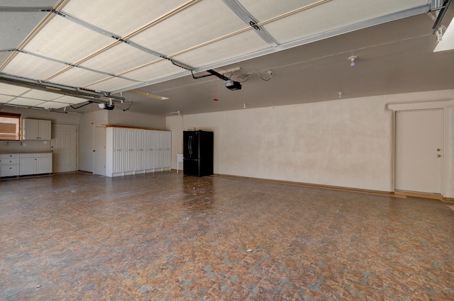 garage featuring a garage door opener and black refrigerator