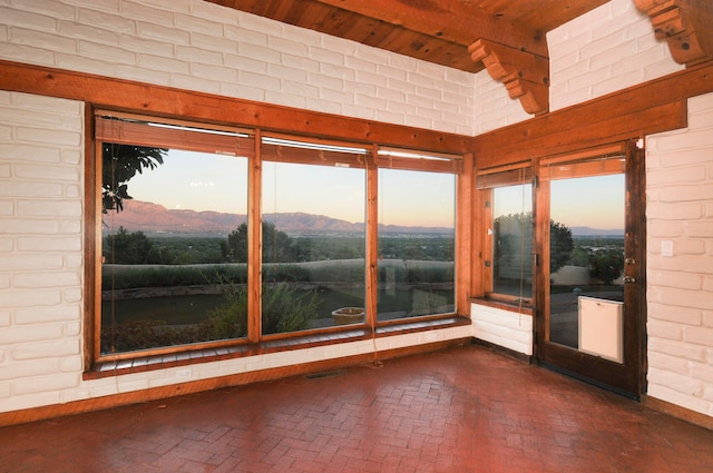 spare room featuring wood ceiling, a mountain view, and brick wall