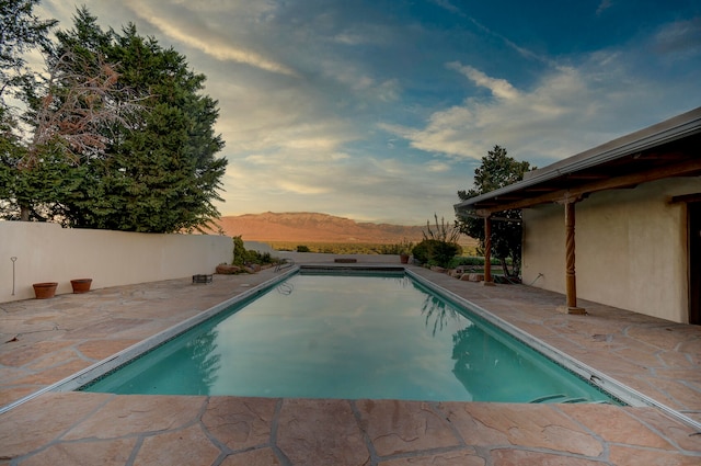 pool at dusk with a patio and a mountain view