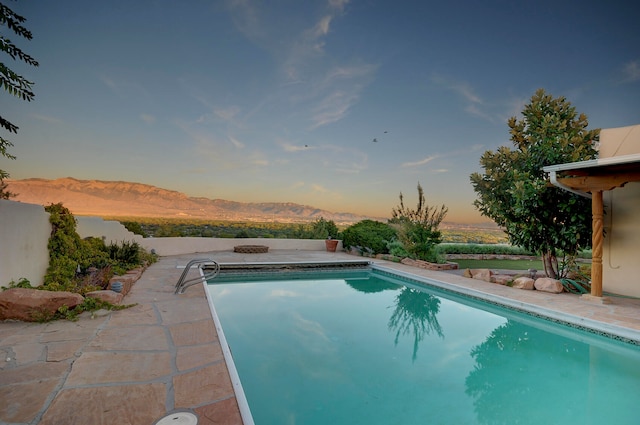 pool at dusk with a patio and a mountain view