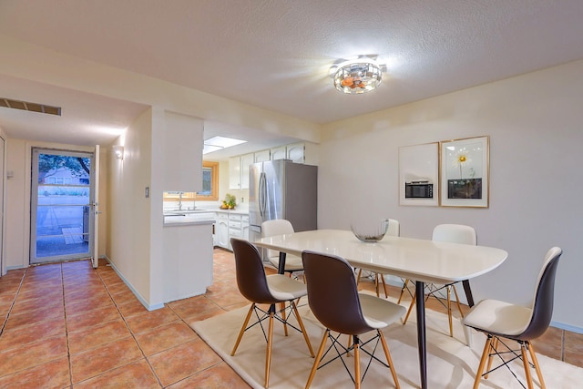 dining room with a textured ceiling, light tile patterned floors, and sink