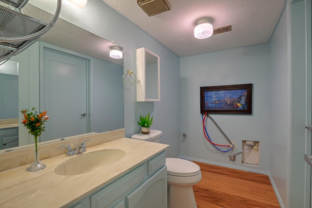 bathroom featuring a textured ceiling, wood-type flooring, vanity, and toilet