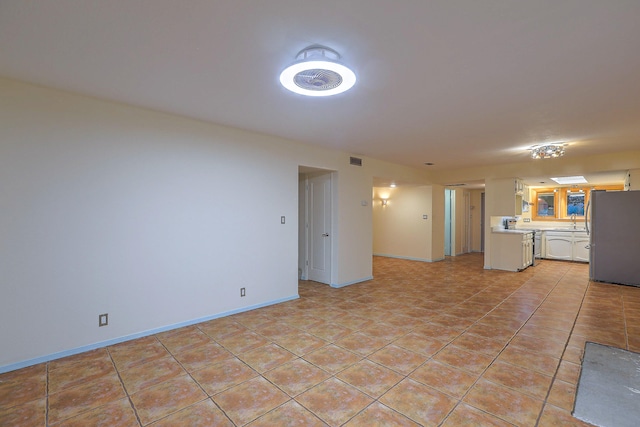 unfurnished living room with light tile patterned flooring and sink