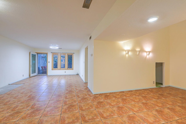 tiled empty room featuring a textured ceiling